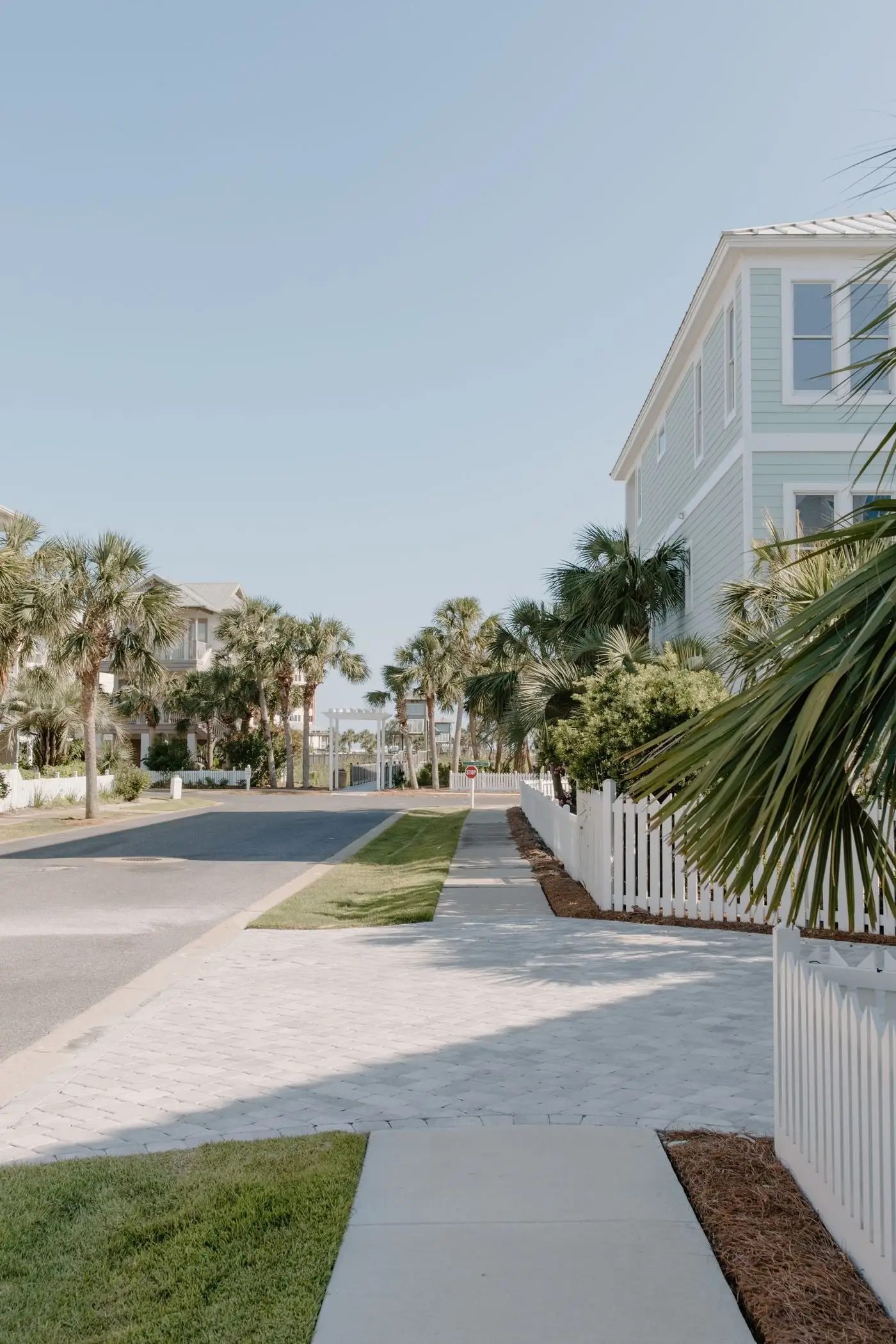 New sidewalk beside a white picket fence and a mulched bed