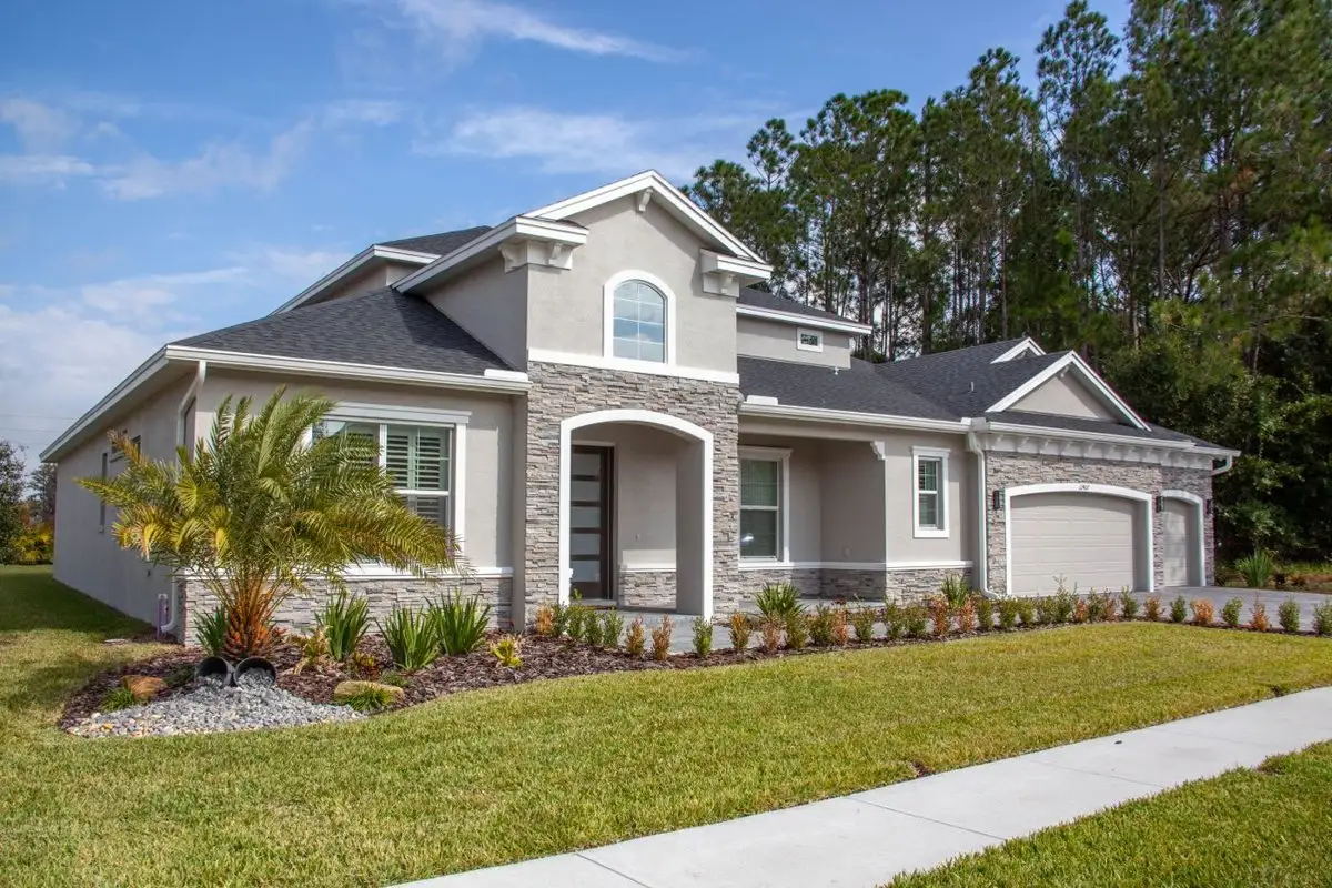 Stucco home with a new green front lawn, a palm and a sidewalk