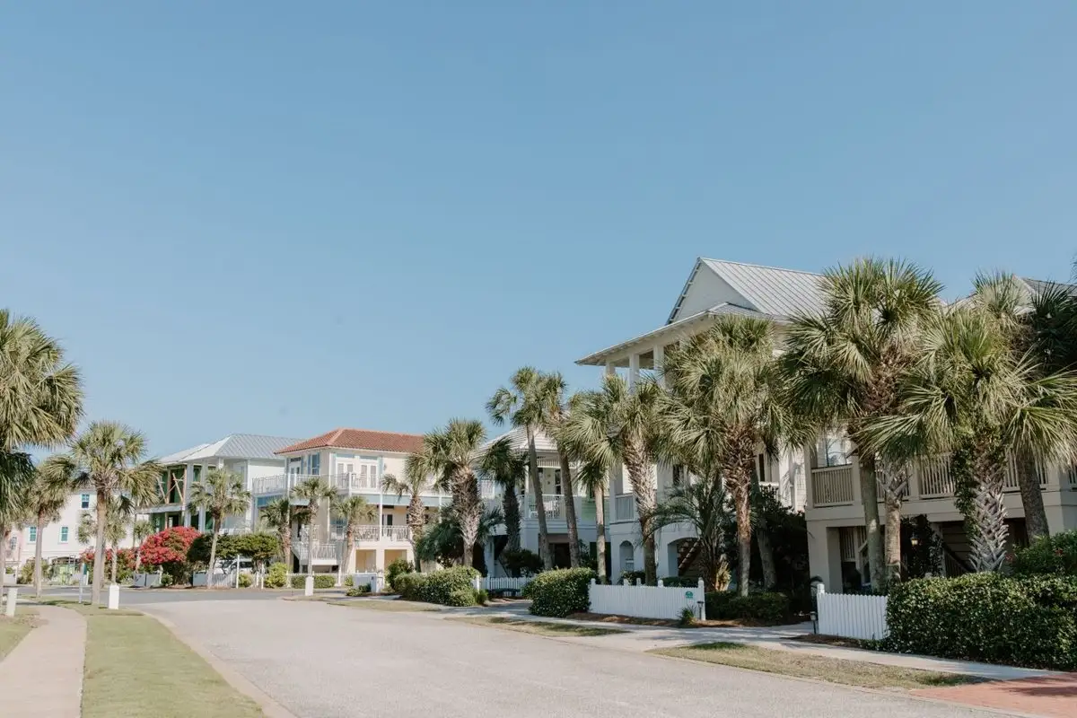 Street of light-colored townhomes with sabal palms and a grass verge